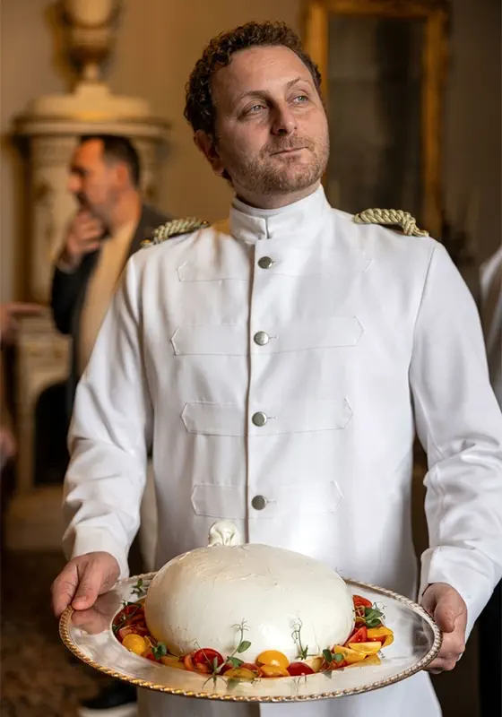 Camisa Essential waiter presenting a large burrata on an ornate silver platter