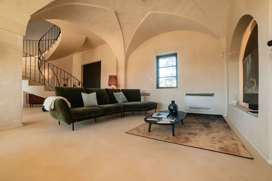 Minimalist living space inside a restored stone building featuring vaulted ceilings, a spiral staircase and contemporary furniture